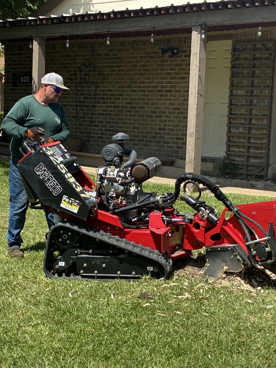 Hunters Tree Solutions operator running a Barreto stump grinder in a Dallas, TX front yard